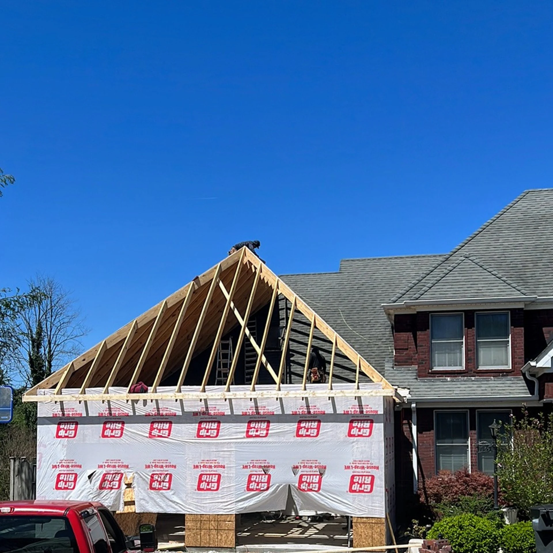 Roof framing for a home addition beside an existing brick house