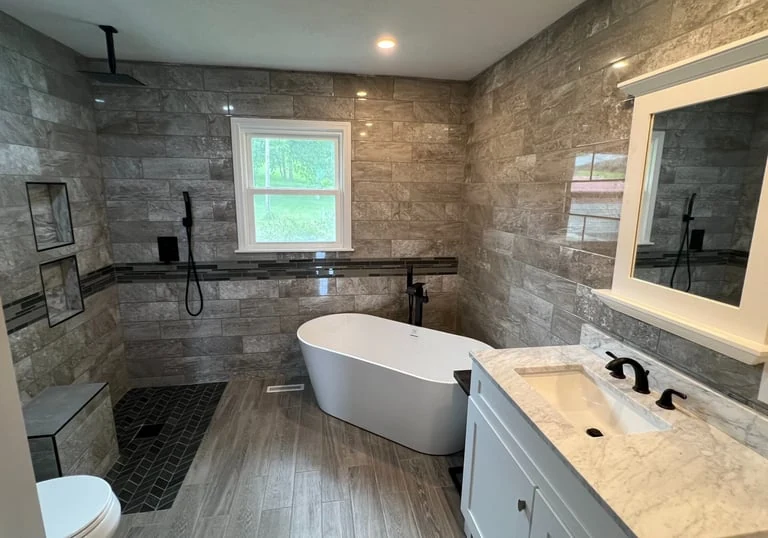 Freestanding bathtub beside a glass shower with stone-look tile