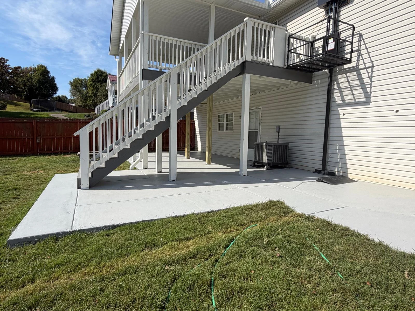 Covered raised deck with white railings, gray stairs and an exterior platform lift
